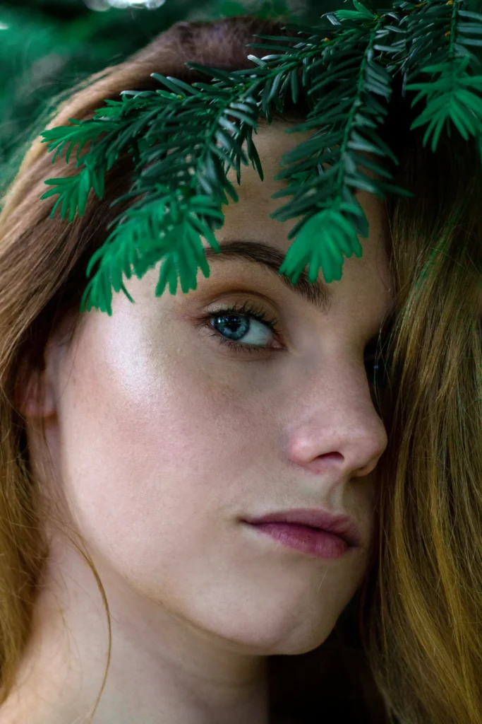 A person with long hair adorned with green cannabis leaves, symbolizing the natural connection between cannabis and skincare in 2025.