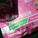 Pink packaging of THC cookies labeled with 10mg THC and 20mg CBD per cookie, highlighting dietary info.